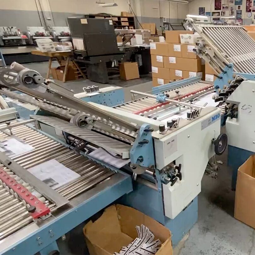 A high-quality commercial printing machine is in a factory with boxes and paper.